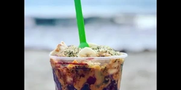 Açaí cup with green straw at the beach